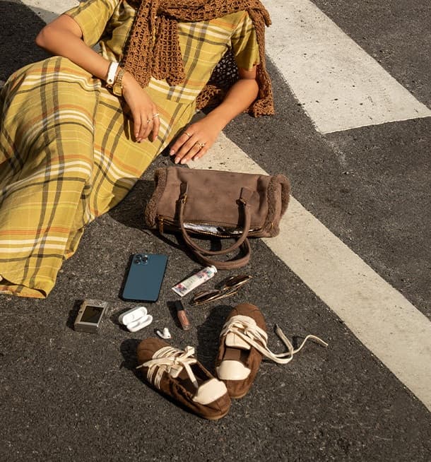 Brown suede Insignia sneakers beside a bag on city asphalt from the Around the City campaign