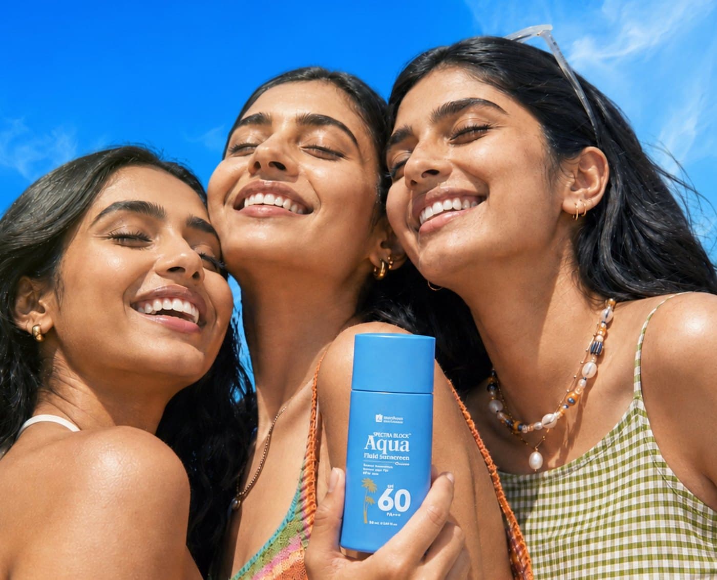 Three women smiling in the sun with a bottle of Jenpharm Spectra Block Aqua SPF 60 sunscreen