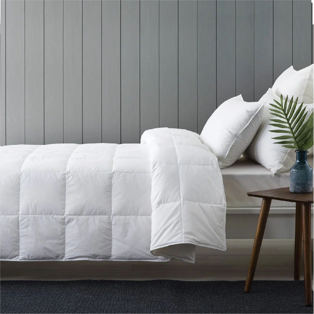 A white quilted duvet on a bed against a grey panelled wall